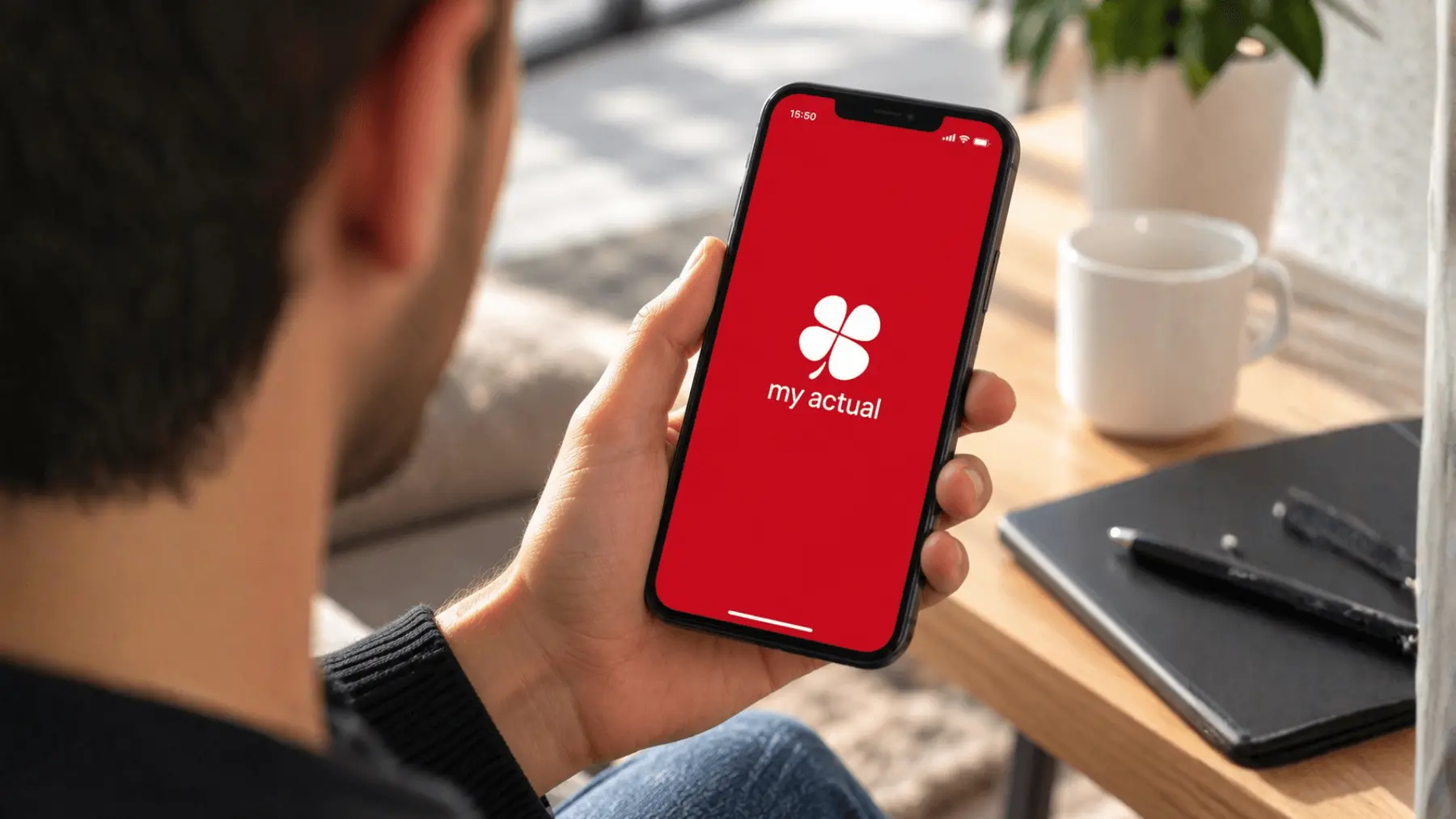 Un homme tient un smartphone affichant l'écran d'accueil de l'application my actual.